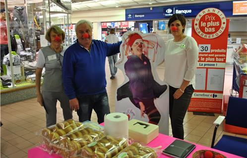 Le président de l'association "Bises de clowns" Jean-Pierre Doucet accompagné de sa femme à gauche. Il est soutenu par Aurélie Saint Pe Dupeyron, responsable caisse du magasin Carrefour, pour l'opération des boucles du cœur.