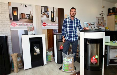 Guillaume à coté d'un poêle Ravelli, avec à ses pieds un sac de granulés de 15 kgs