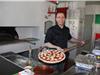 Franck Mari avec fierté présente une pizza réalisée avec des ingrédients de grande qualité.