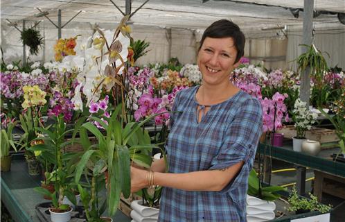 Hélène Jacq tenant dans ses mains une orchidée haut de gamme... pour les collectionneurs.